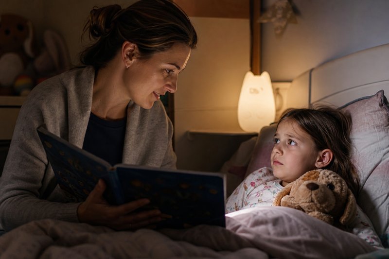Caregiver reading children's books at bedtime while a child processes big feelings