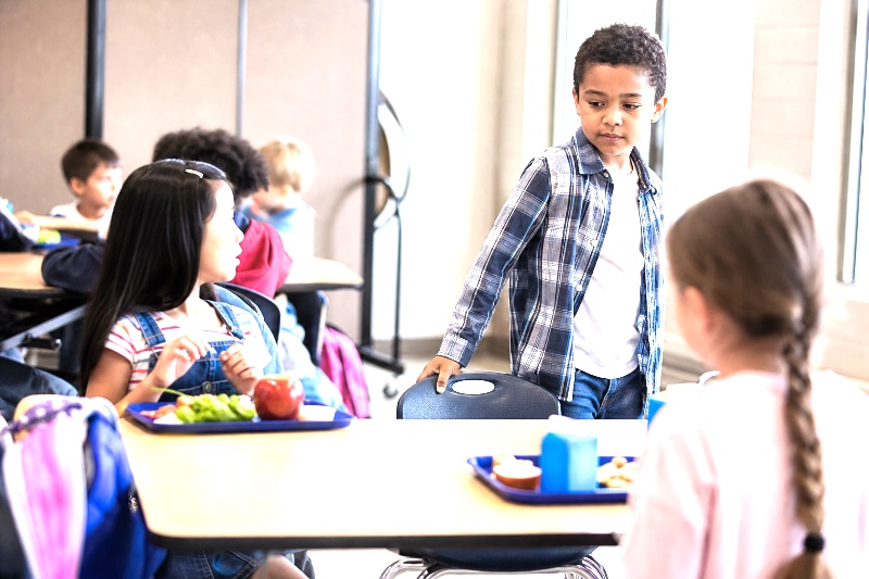 Blog post featured image of children sharing a lunch table, showing empathy in a school setting